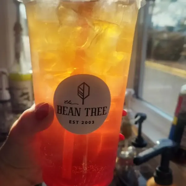 Tall layered iced drink fading from gold to red in a Bean Tree cup