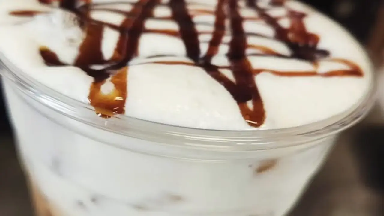 Iced latte with thick cold foam and a crosshatched chocolate drizzle